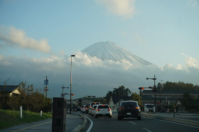 several cars on a road driving toward mount fuji