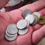 A hand holding several Japanese yen coins